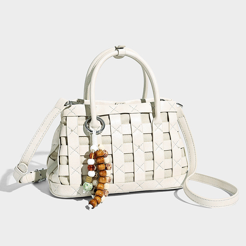 Small structured woven satchel tote with rounded top handles, silver-tone ring hardware, and bead tassel charm, front view