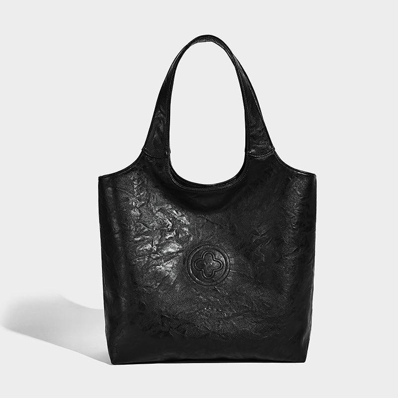 Large open-top tote bag with crinkled leather-look finish, long double shoulder straps, and embossed circular detail on
