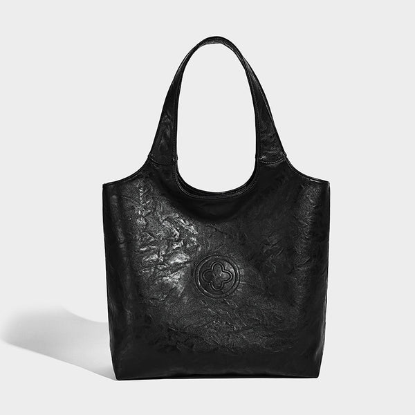 Large open-top tote bag with crinkled leather-look finish, long double shoulder straps, and embossed circular detail on
