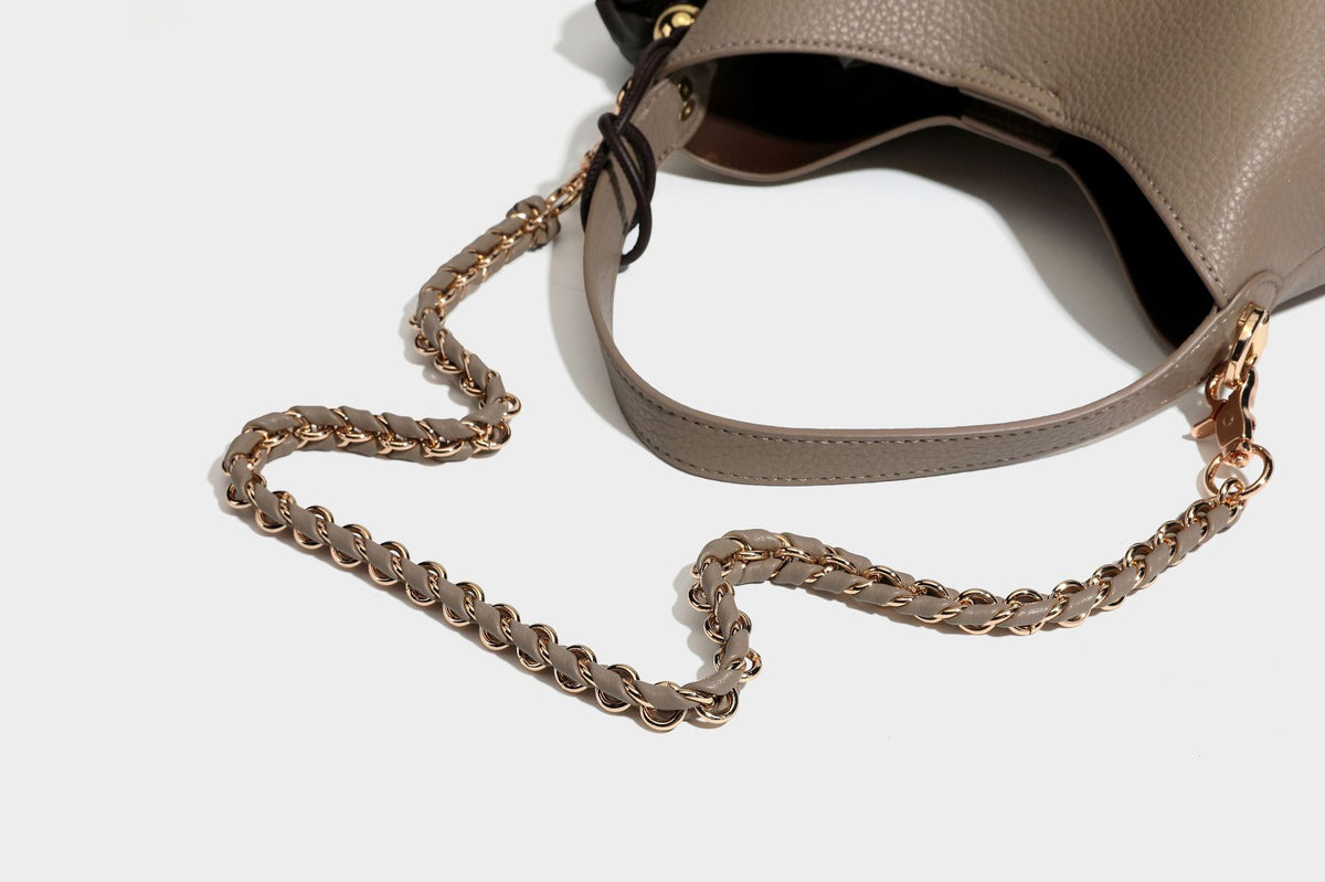Schultertasche in genarbter Lederoptik im Hobo-Stil mit goldfarbener Kette, kurzem Tragegriff und dekorativem Anhänger an der Seite, Detailansicht
