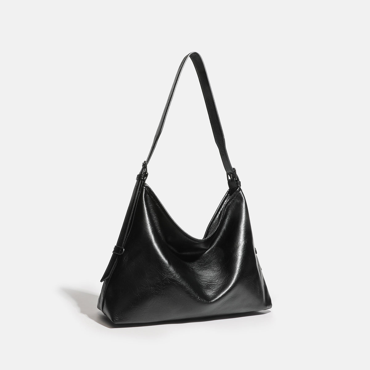 Slouchy large black leather-look shoulder bag with zipper closure, wide flat base, and long adjustable strap, detail view 2