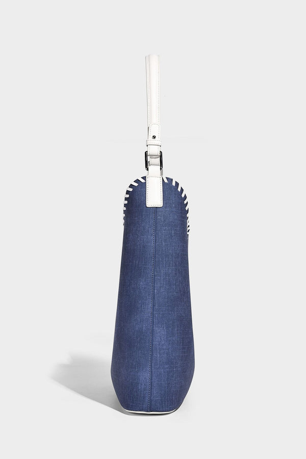Denim-blue hobo tote with white leather-look shoulder strap, contrast whipstitch trim along curved open top, and silver-tone