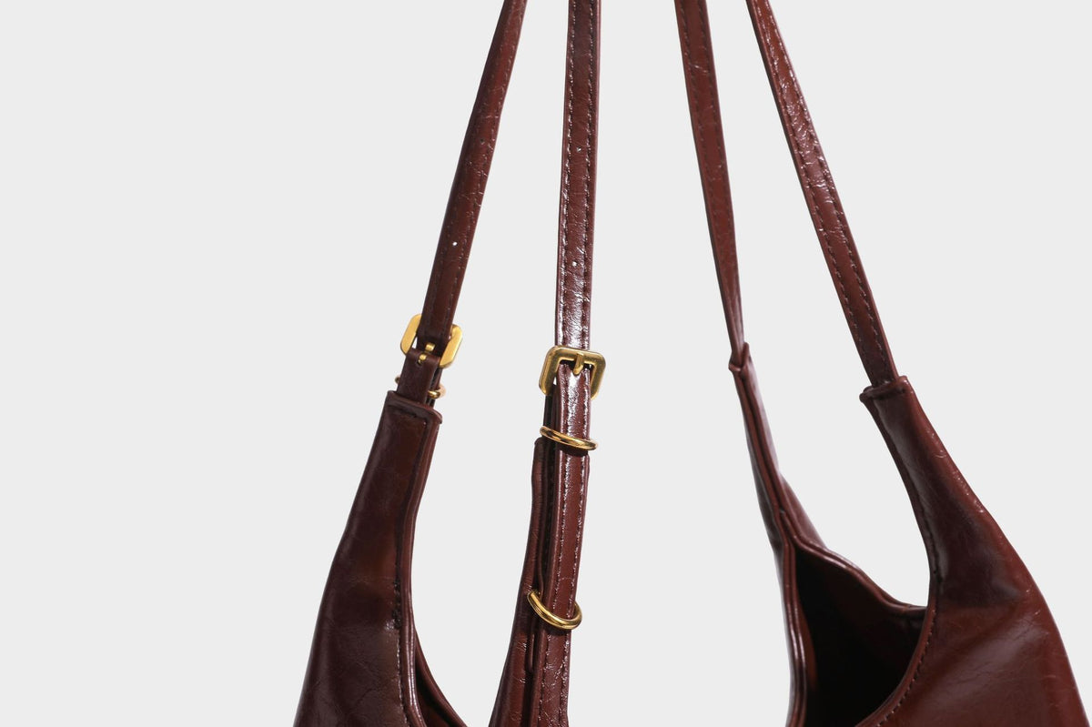 Locker fallende Hobo-Schultertasche mit offenem Oberteil aus glänzendem, geknautschtem Lederimitat in Dunkelbraun, mit schmalem verstellbarem Riemen und goldfarbenem