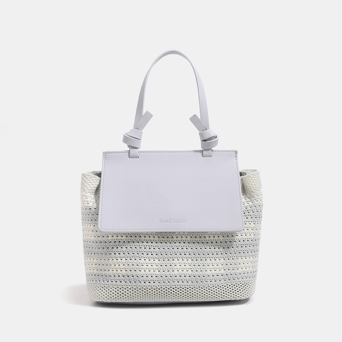 Structured woven tote bag with smooth leather-look front flap panel, knotted top handles, and detachable crossbody strap