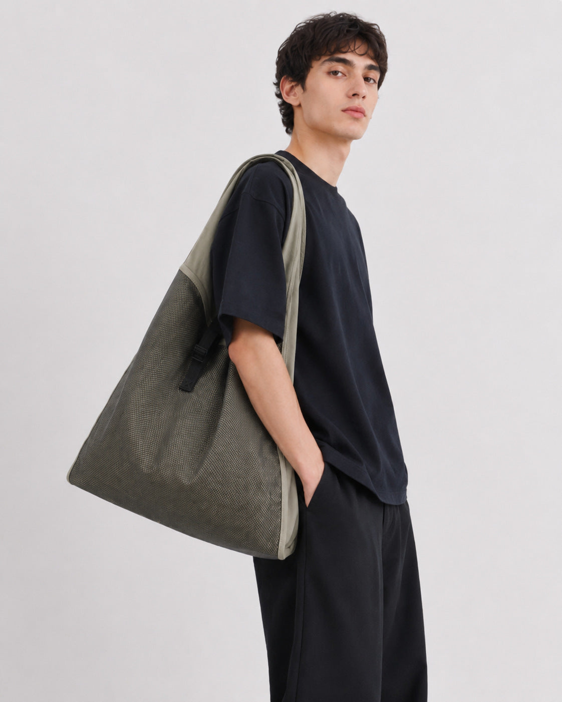 Oversized triangular mesh tote bag with matte olive-khaki fabric straps and trim, dark open-weave mesh body, matte black