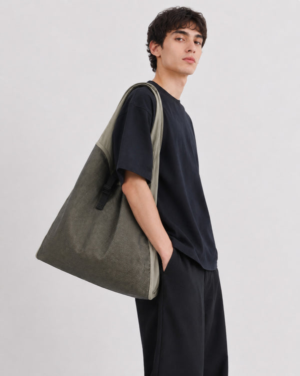Oversized triangular mesh tote bag with matte olive-khaki fabric straps and trim, dark open-weave mesh body, matte black