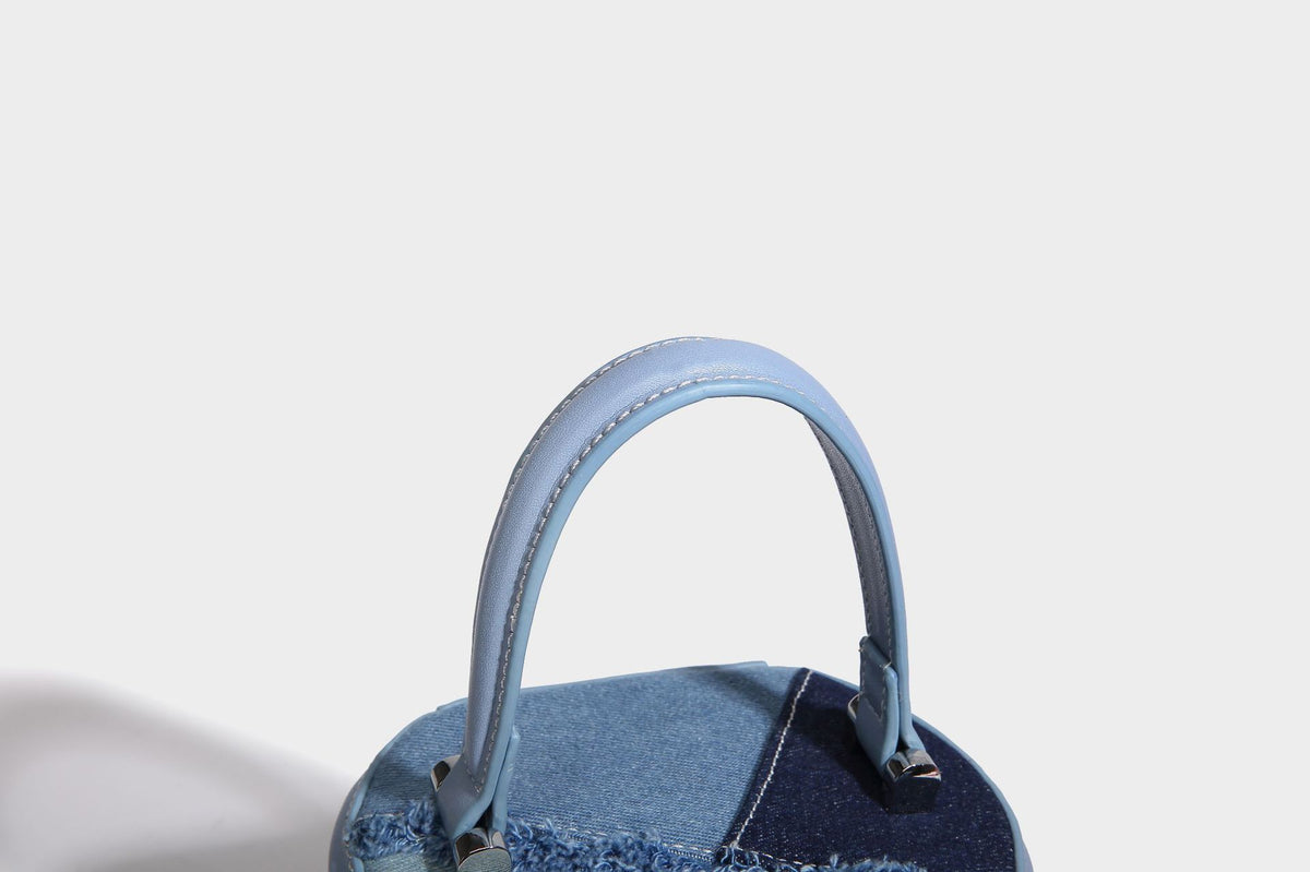 Mini cylindrical barrel bucket bag in denim patchwork with frayed edges, smooth leather-look trim, zip-around top closure