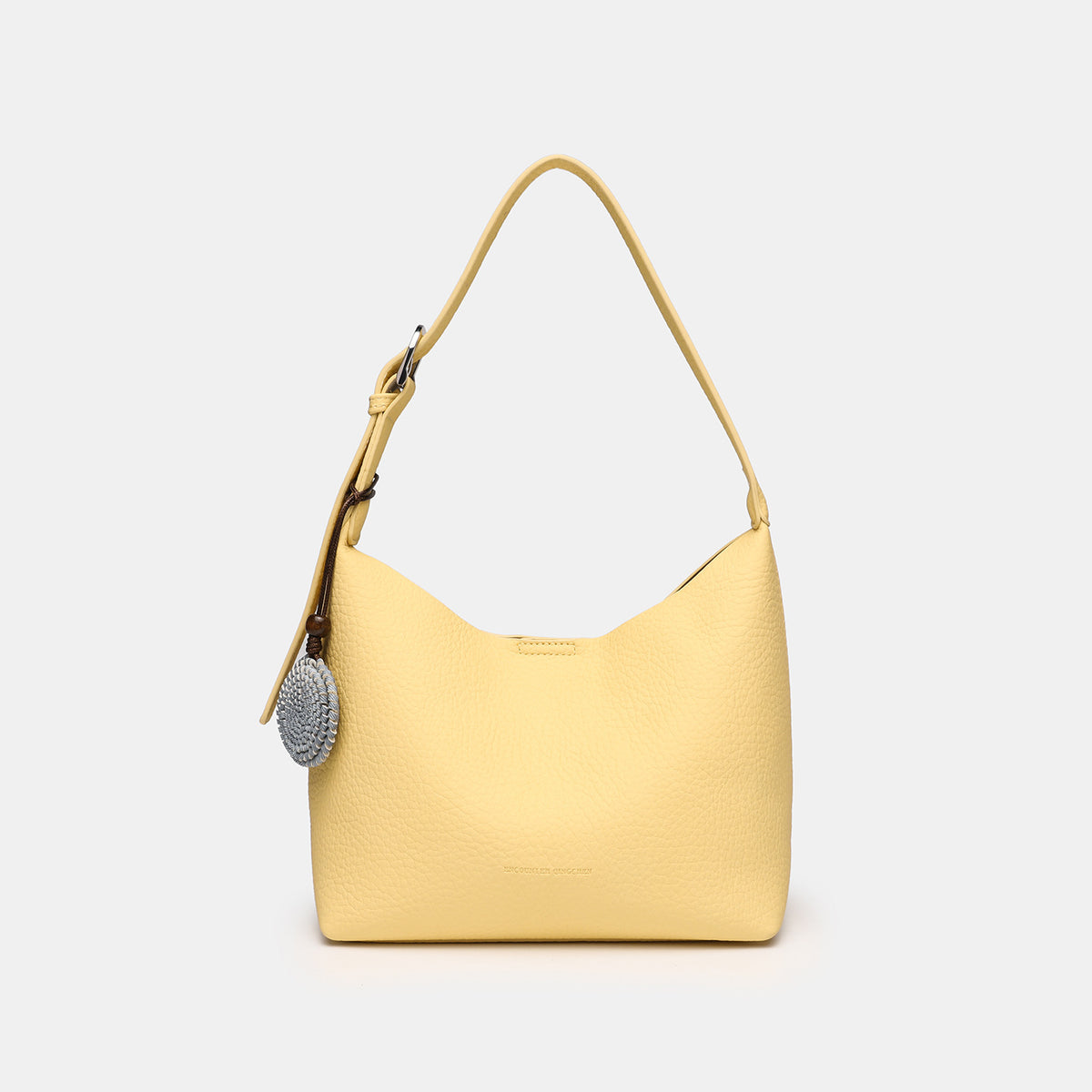 Slouchy hobo shoulder bag in pale yellow pebbled texture with woven charm, adjustable strap, matching zip pouch, and, detail