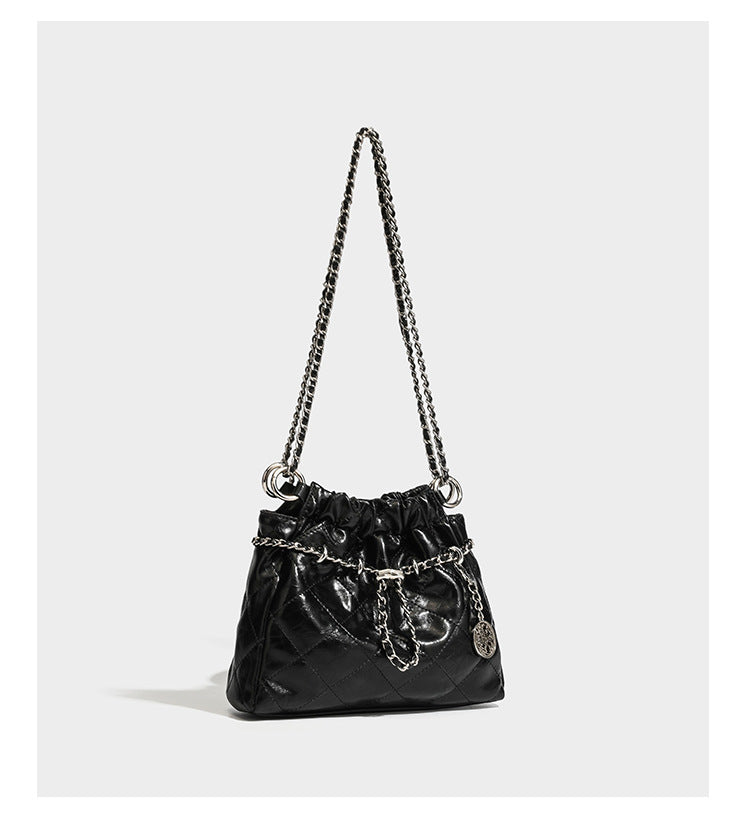 Glossy diamond-quilted drawstring bucket bag with silver chain shoulder strap and medallion charm, detail view 10