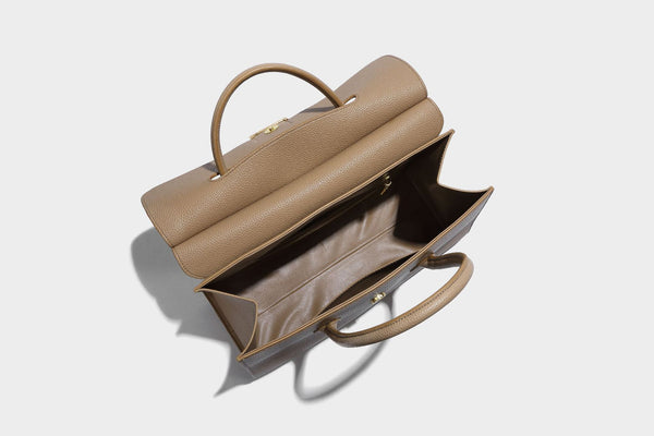 Strukturierte, trapezförmige Henkeltasche mit matt genarbter Oberfläche, vorderer Klappe und quadratischem Drehverschluss in Goldoptik, Detailansicht