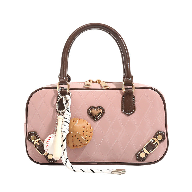 Blush pink quilted bowling barrel bag with dark brown leather-look trim and handles, baseball bat and ball charm, gold-tone