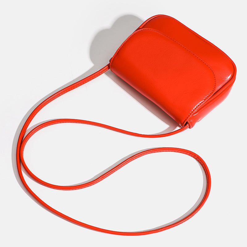 Compact rounded rectangular flap crossbody bag with glossy leather-look finish and long shoulder strap, detail view 4