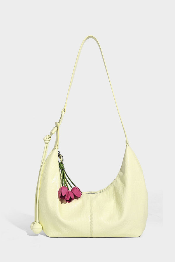 Slouchy crescent half-moon shoulder bag in pink pebbled textured finish with floral charm and knotted side detail, detail