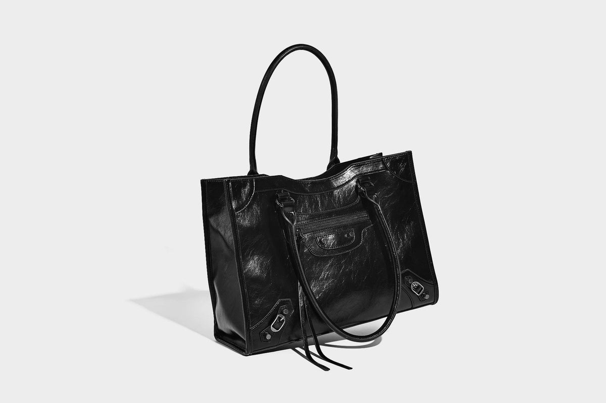 Large structured leather-look tote bag with front zip pocket, moto hardware accents, and long double shoulder straps, detail