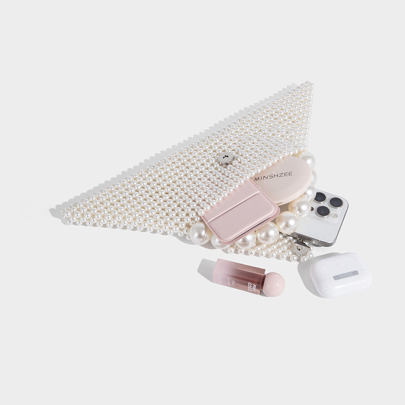Small structured triangle clutch bag covered in glossy pearl beads with an arched pearl top handle and silver snap closure