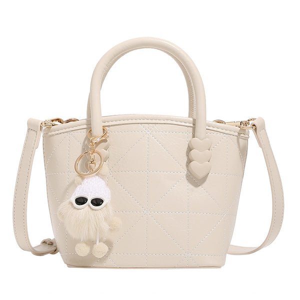 Quilted leather-look mini bucket tote bag with heart-shaped side accents, gold-tone hardware, fuzzy character charm, and