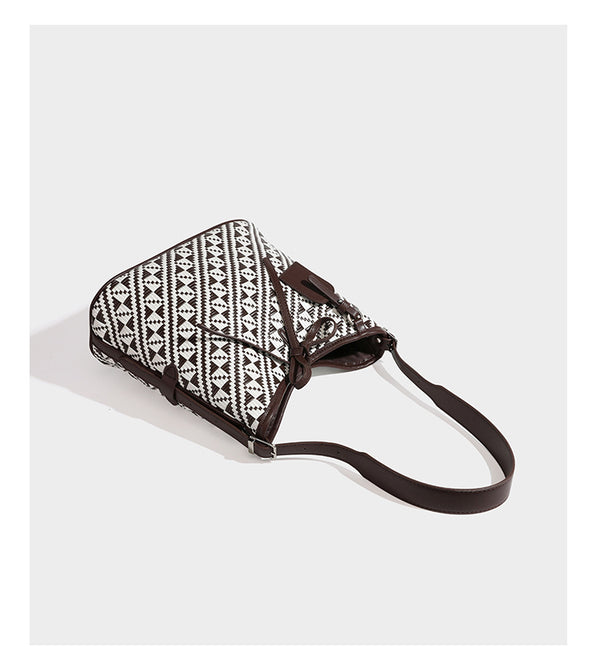 Woven geometric bucket shoulder bag in white and dark brown two-tone pattern with leather-look trim and drawstring top