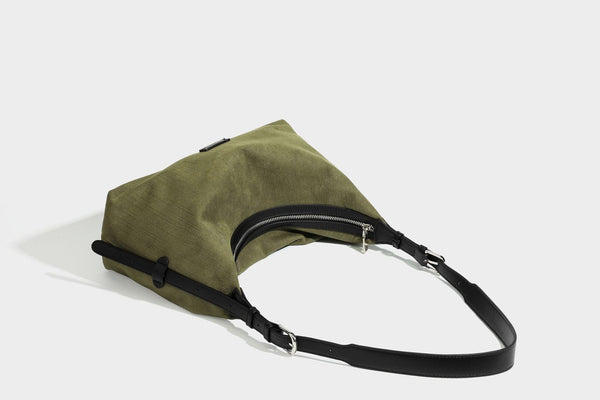 Slouchy olive green canvas hobo shoulder bag with black leather-look trim, zip-top closure, and adjustable strap, detail view