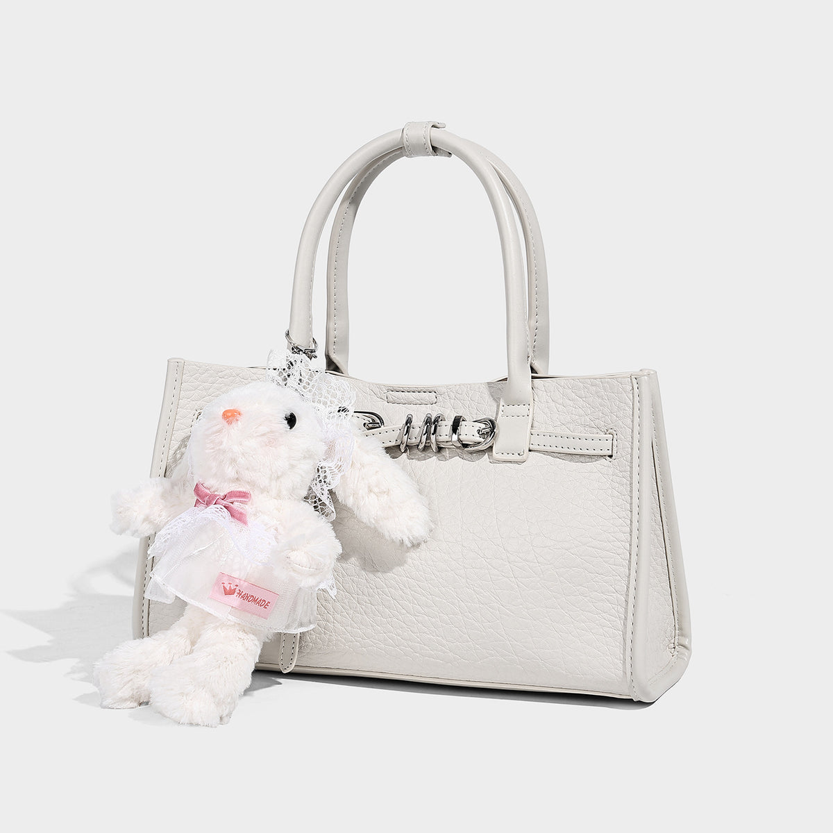 Structured trapezoid tote bag in pebbled leather-look finish with double top handles, silver-tone bar hardware, and, detail