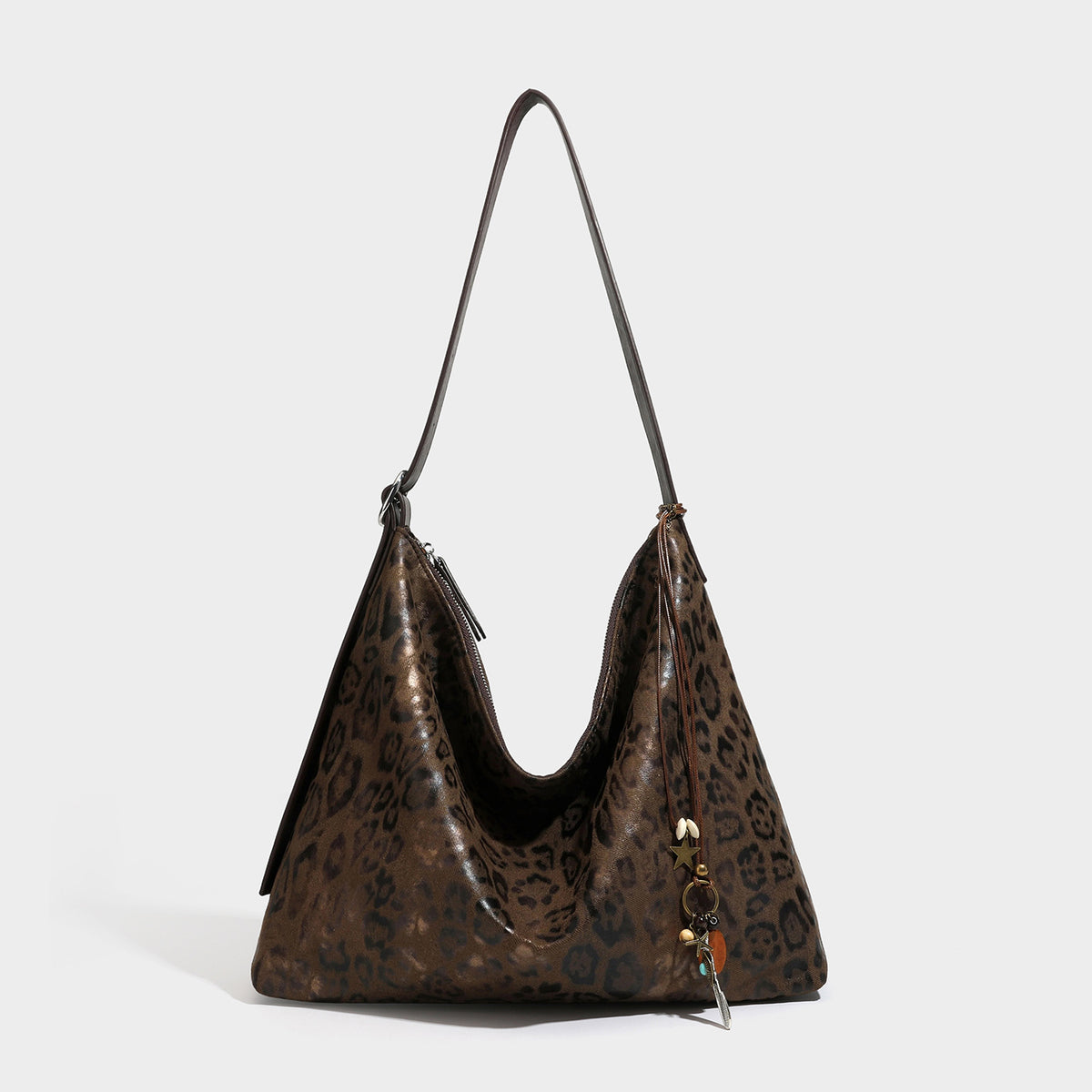 Slouchy leopard print hobo shoulder bag with glossy coated finish, top zipper closure, dark brown trim, and dangling charm