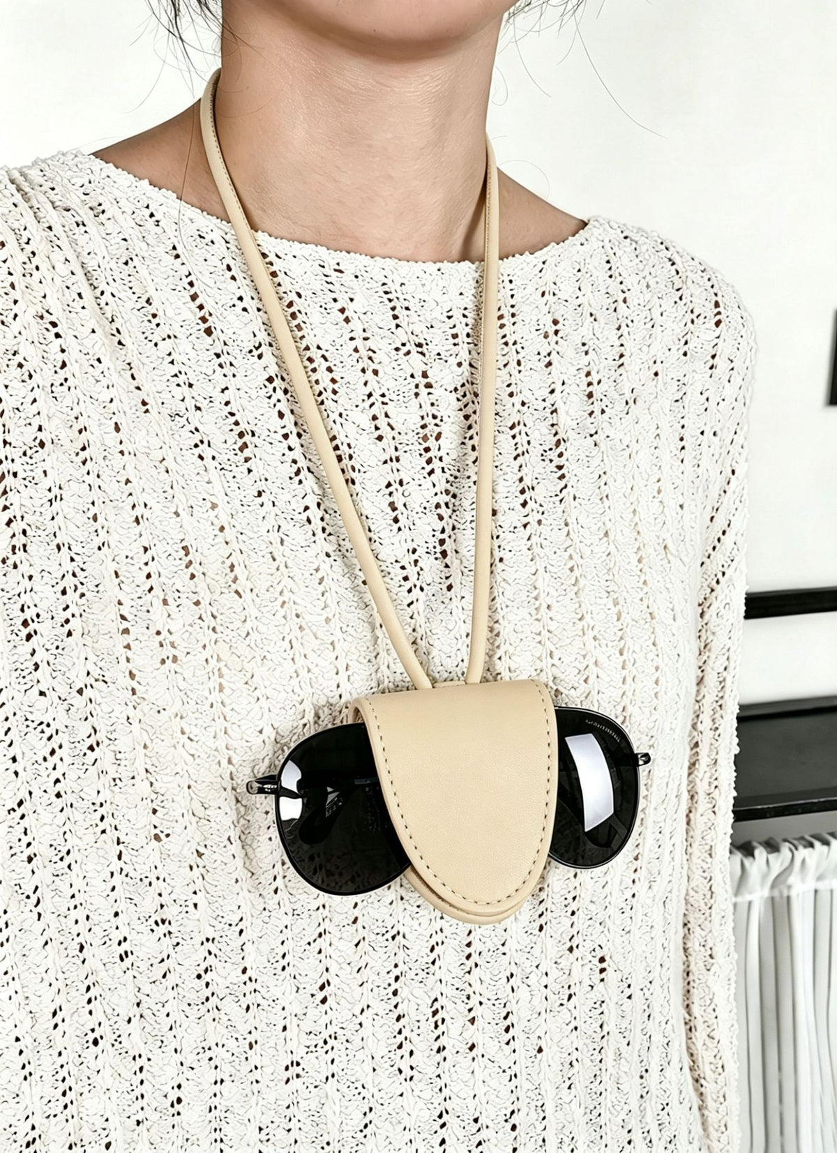 Small woven crescent shoulder bag with leather-look trim, zip closure, silver-tone ring hardware, and beaded tassel charm