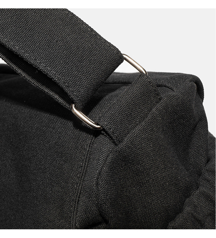 Große schwarze Messenger-Tasche aus mattem Canvas mit Überschlag vorn, Reißverschluss oben, elastischen Seitentaschen und verstellbarem silberfarbenem