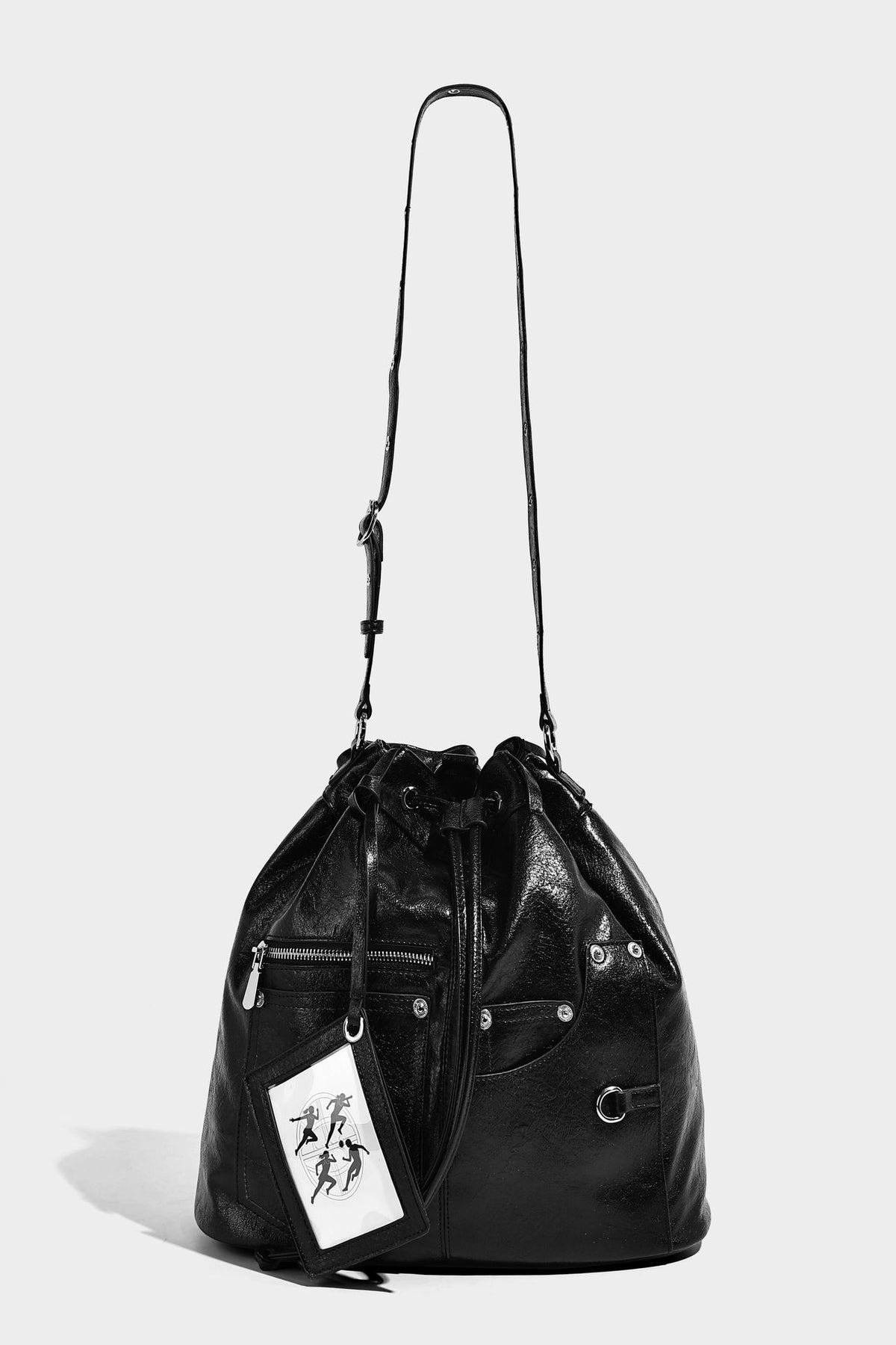 Glossy black convertible bucket backpack with silver grommet-studded straps, drawstring cinch closure, and front zip pocket