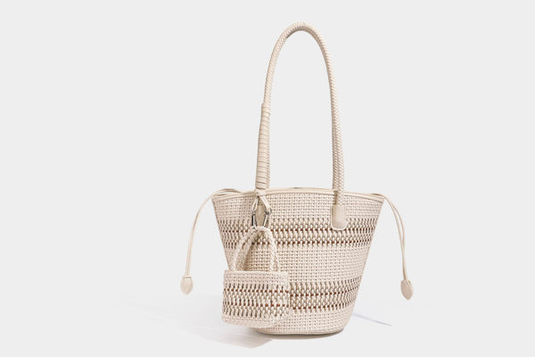 Light blue open-weave woven bucket tote bag with long braided shoulder straps, drawstring side ties, and attached mini pouch