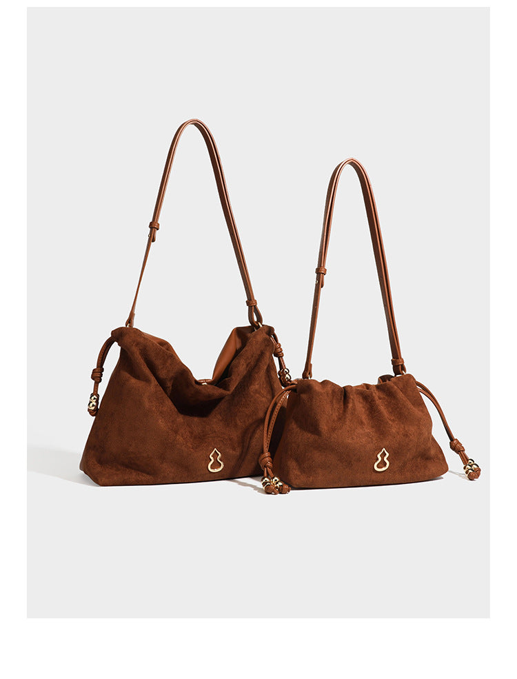 Suede-look drawstring shoulder bag in brown with smooth trim, knotted bead drawstring closure, slim adjustable strap, and