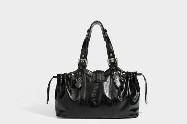 Large black glossy leather-look tote bag with silver buckle straps, eyelet grommet panels, drawstring side gathers, and