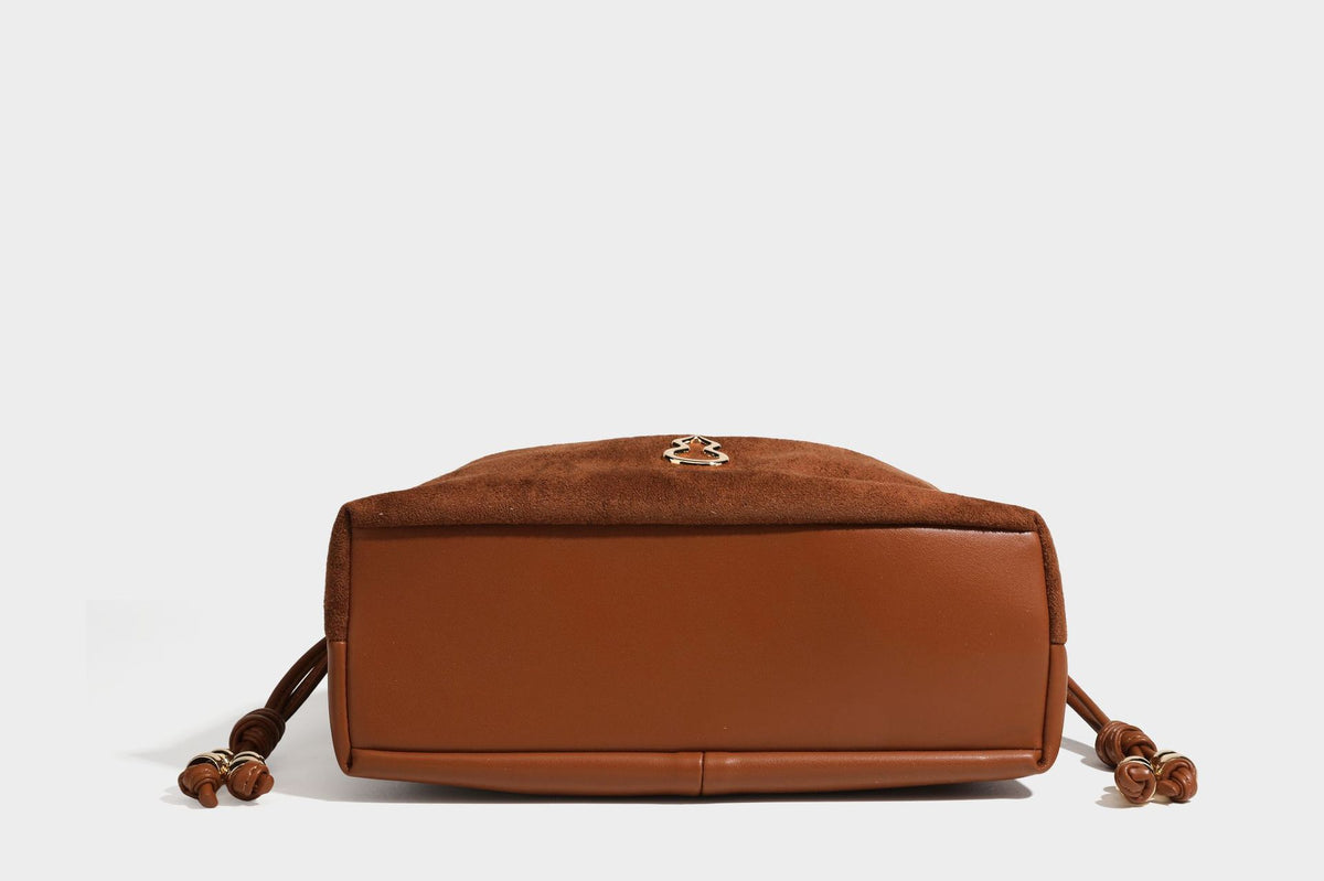 Suede-look drawstring shoulder bag in brown with smooth trim, knotted bead drawstring closure, slim adjustable strap, and
