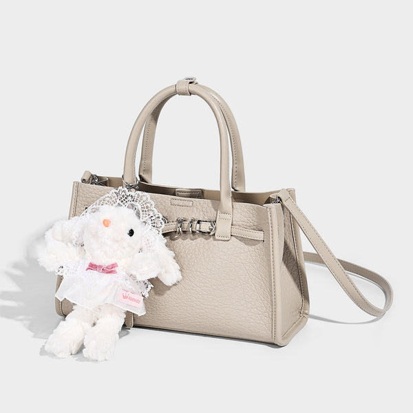 Structured trapezoid tote bag in pebbled leather-look finish with double top handles, silver-tone bar hardware, and, detail
