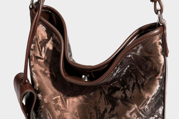Große Hobo-Schultertasche mit Crinkle-Glanzfinish in Dunkelbraun, schmalem verstellbarem Riemen, geknoteten Beschlägen und seitlich befestigter Klappe