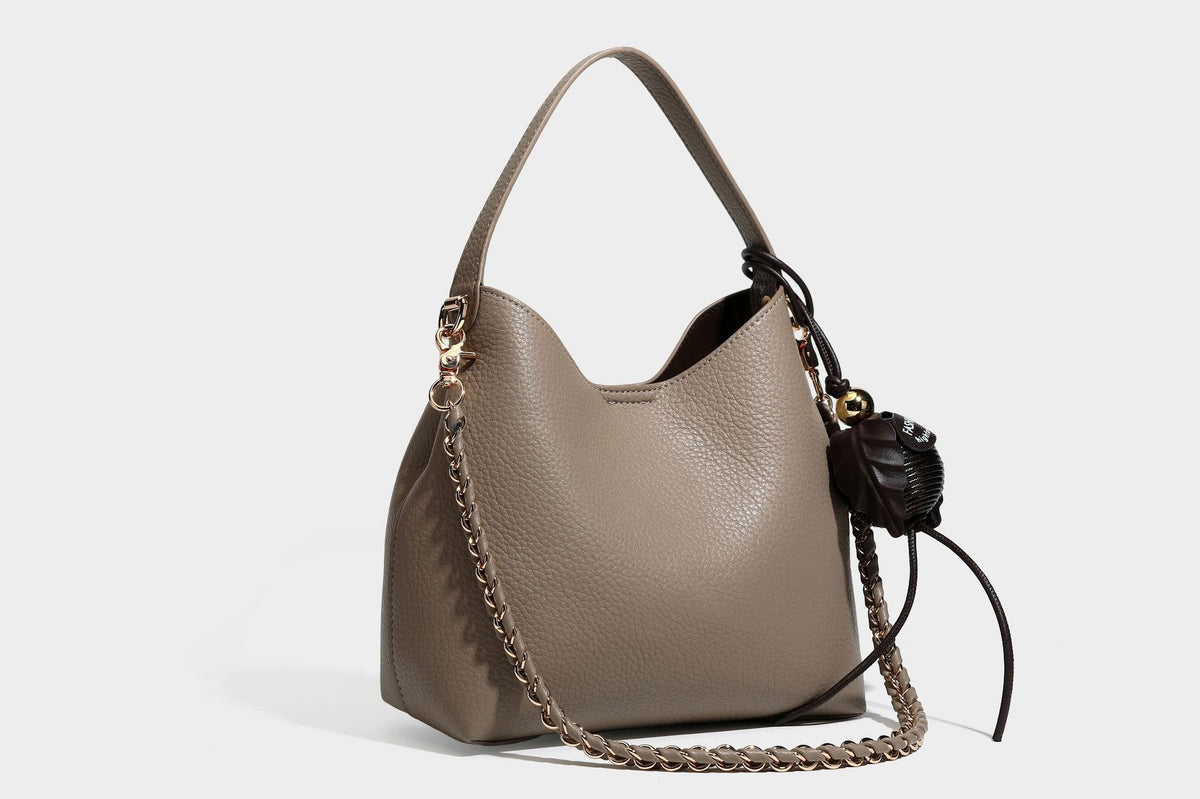 Schultertasche in genarbter Lederoptik im Hobo-Stil mit goldfarbener Kette, kurzem Tragegriff und dekorativem Anhänger an der Seite, Detailansicht