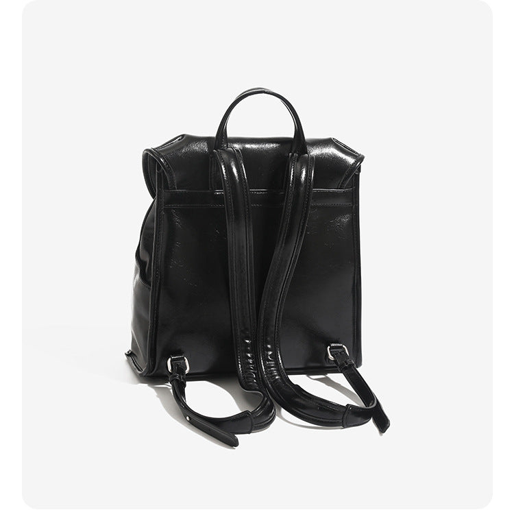 Structured glossy leather-look flap backpack handbag with dual buckle closures, top handle, and silver-tone hardware, detail