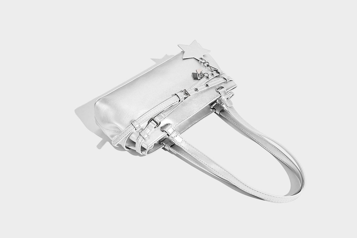 Structured glossy leather-look shoulder bag with wraparound belt straps, silver-tone hardware, and dangling star charm