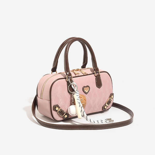Blush pink quilted bowling barrel bag with dark brown leather-look trim and handles, baseball bat and ball charm, gold-tone