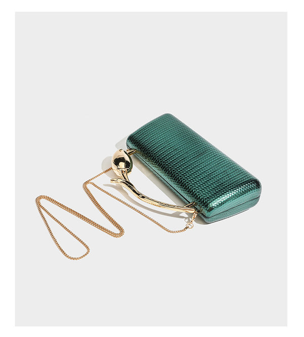 Structured rectangular metallic woven clutch bag with sculptural gold-tone leaf top handle and detachable chain strap, detail