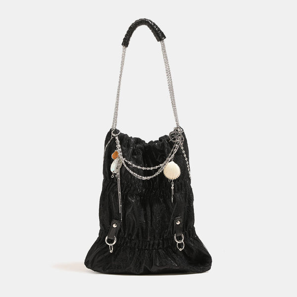 Slouchy lace-overlay bucket bag with silver chain strap, draped chain detail, shell charms, and drawstring top closure