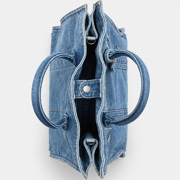 Large washed denim patchwork tote bag with snap-flap front pockets, rolled handles, and detachable shoulder strap, detail