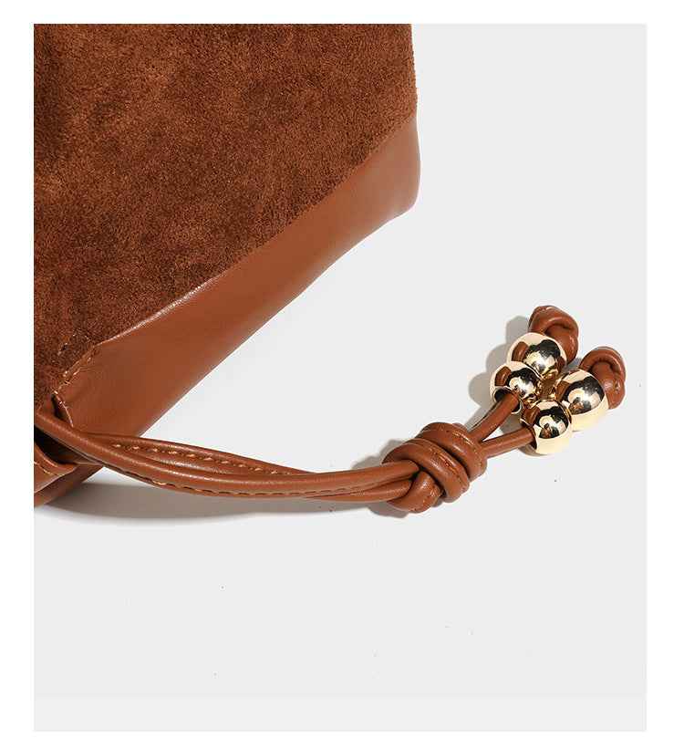 Suede-look drawstring shoulder bag in brown with smooth trim, knotted bead drawstring closure, slim adjustable strap, and