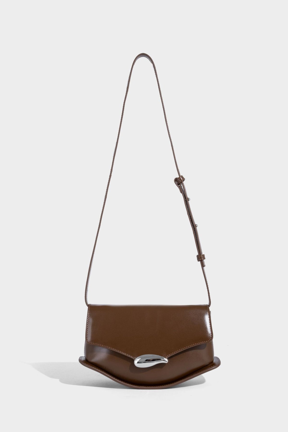 Small structured saddle bag with glossy leather-look finish, angular flap front, silver-tone metal clasp, and slim