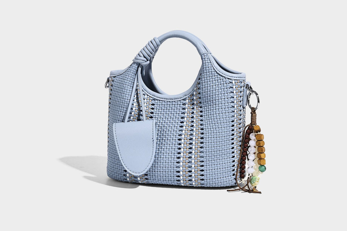 Geflochtene Bucket-Tote in Pastellblau mit geflochtenen Tragegriffen, vorderem Steckfach, Perlenanhänger und abnehmbarem Crossbody-Riemen