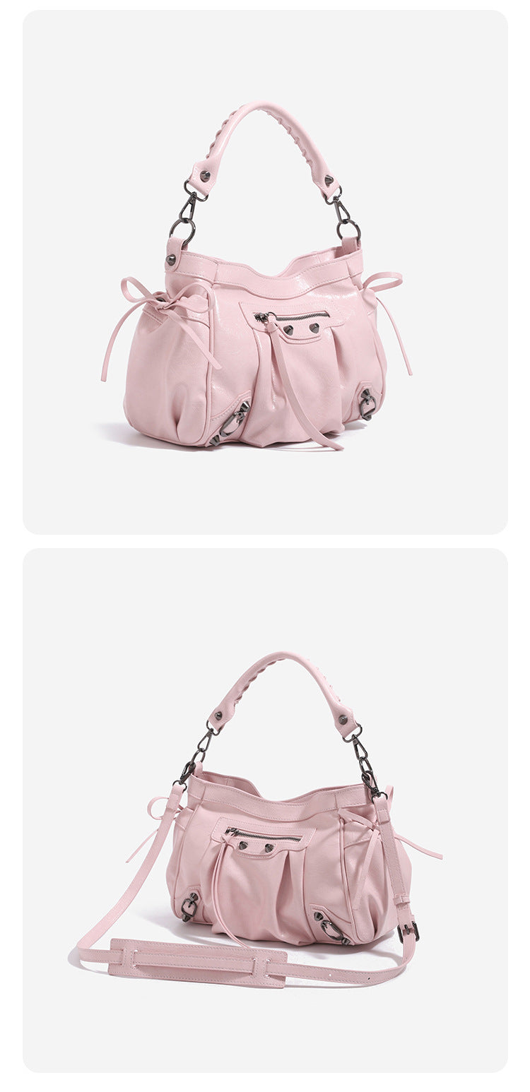 Glossy ruched leather-look shoulder bag with silver stud hardware, fringe trim, front zip pocket, and top handle, detail view