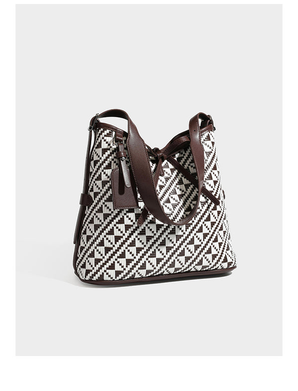Woven geometric bucket shoulder bag in white and dark brown two-tone pattern with leather-look trim and drawstring top