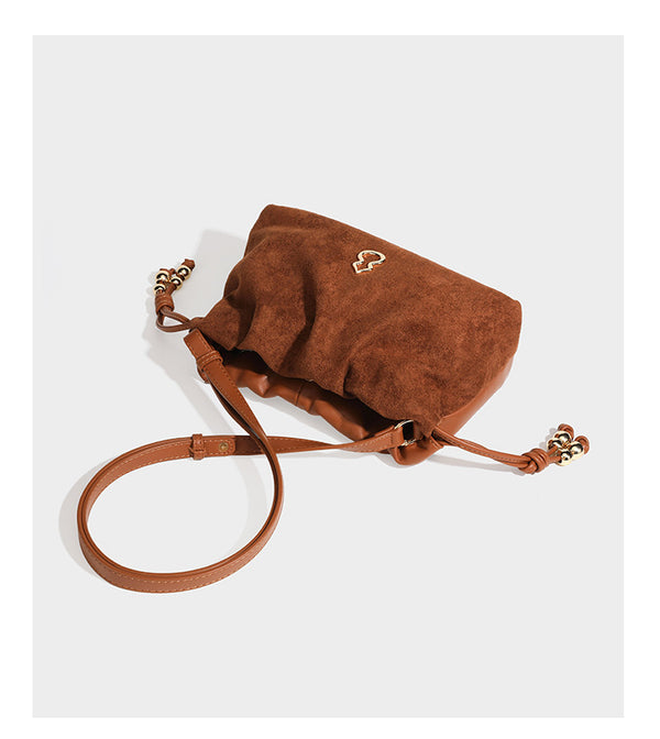 Suede-look drawstring shoulder bag in brown with smooth trim, knotted bead drawstring closure, slim adjustable strap, and