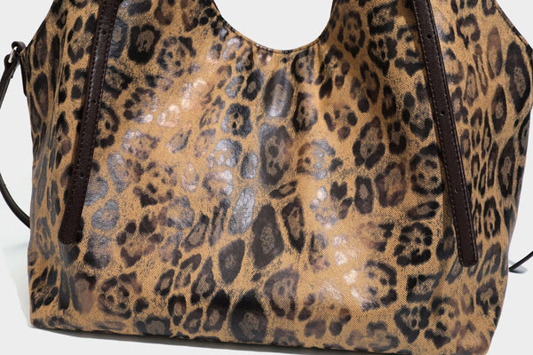 Slouchy leopard-print shoulder tote bag in tan and brown with long double straps, side tie straps, and dangling charm, detail