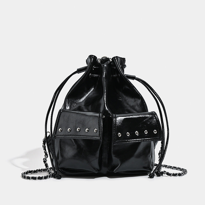 Glossy leather-look drawstring bucket bag with silver dome studs and chain shoulder strap, front view