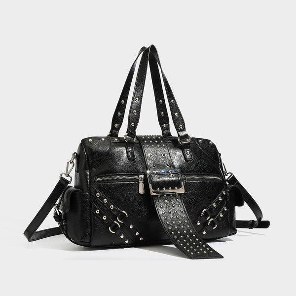 Structured pink leather-look satchel bag with gunmetal studded trim, rectangular buckle strap, dual top handles, and, detail