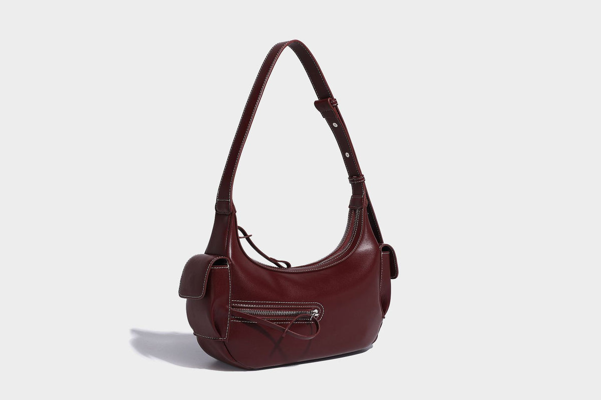 Smooth leather-look crescent shoulder bag with front zip pocket, side flap pockets, adjustable strap, and silver-tone, detail